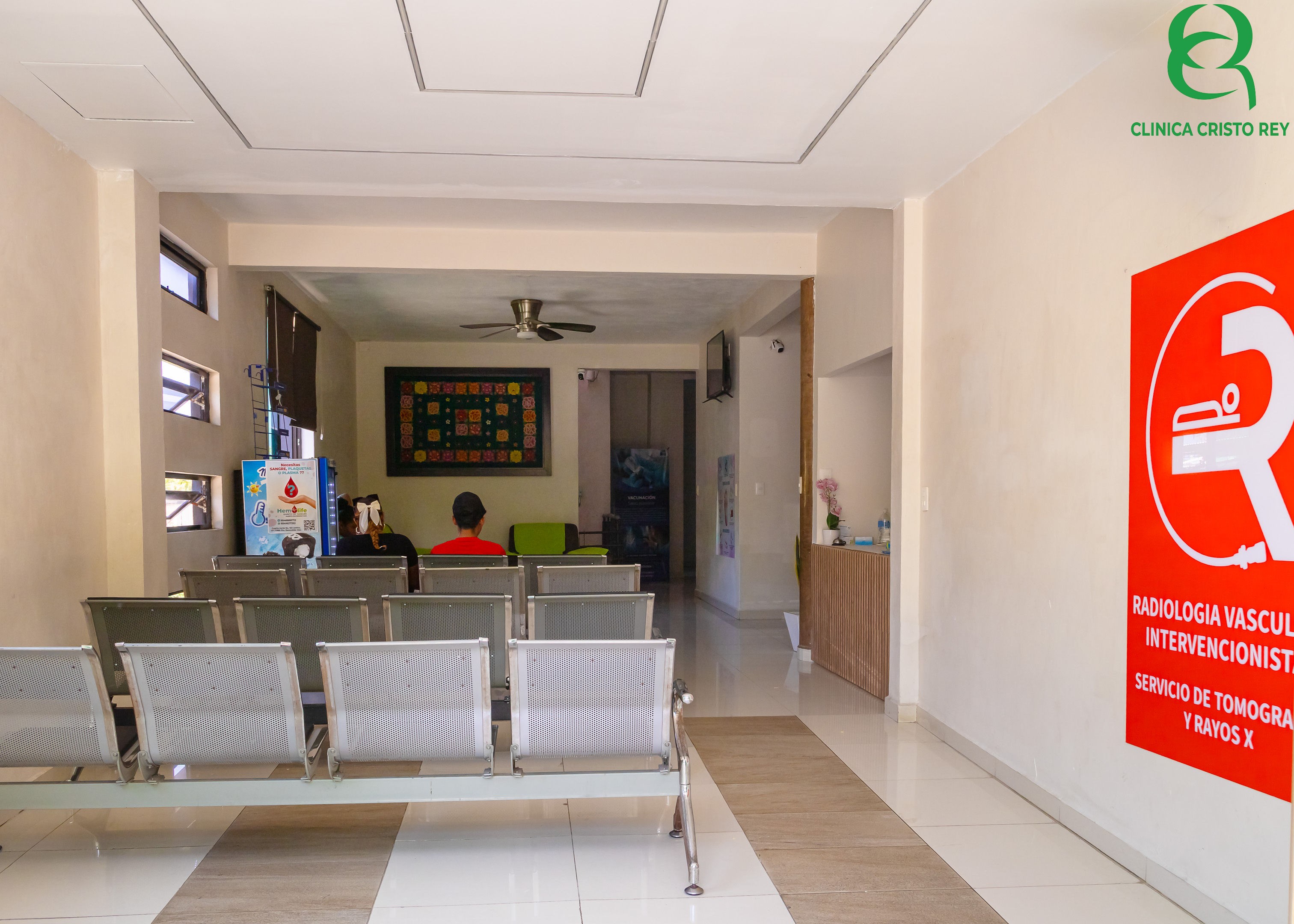 Sala de espera interior con señalética de tomografía y rayos X